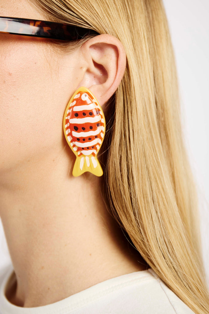 red and yellow fish earring on model ear