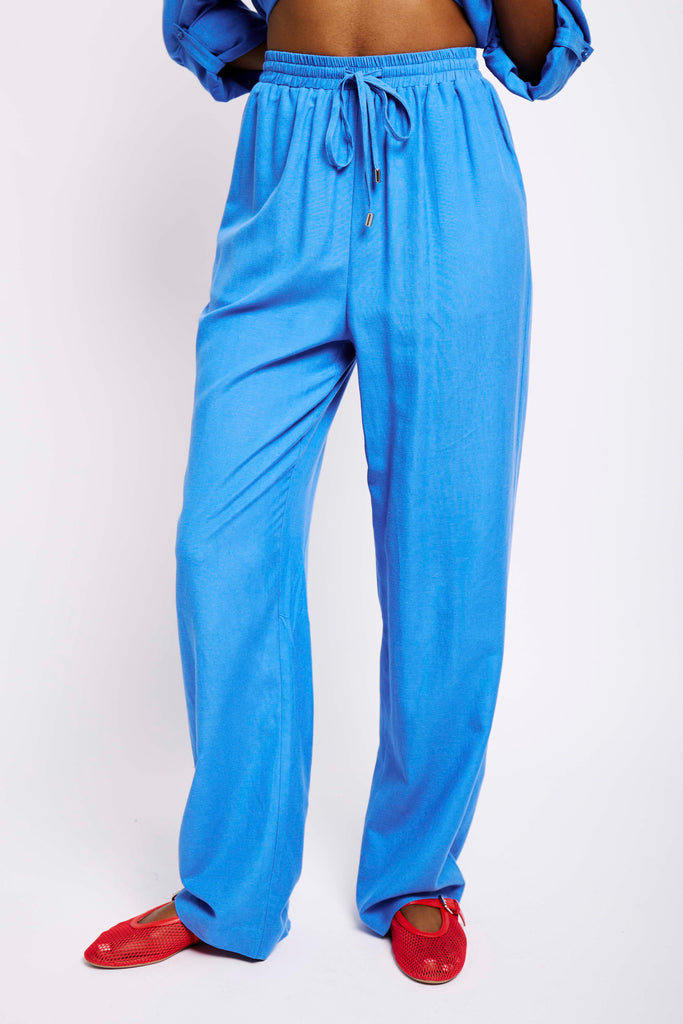 Model wearing blue linen pants and red pumps