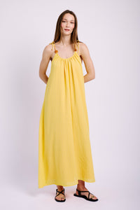 Model wearing yellow sun dress with black sandals.