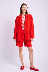 Model wearing red tailored blazer with tailored short and red pumps