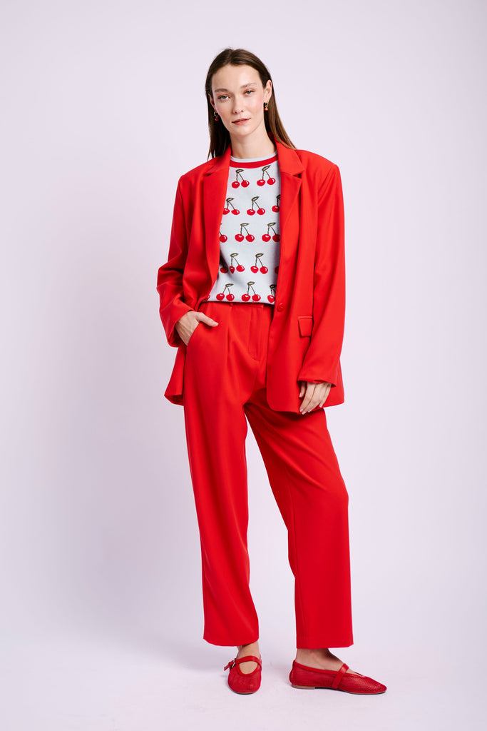 model wearing red suit and cherry jumper 