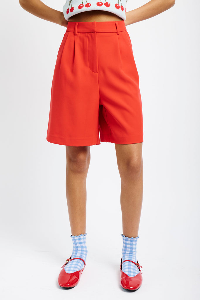 Model wearing red pleated shorts, socks and red shoes