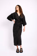 Model is wearing a linen black wrap dress with black sandals 