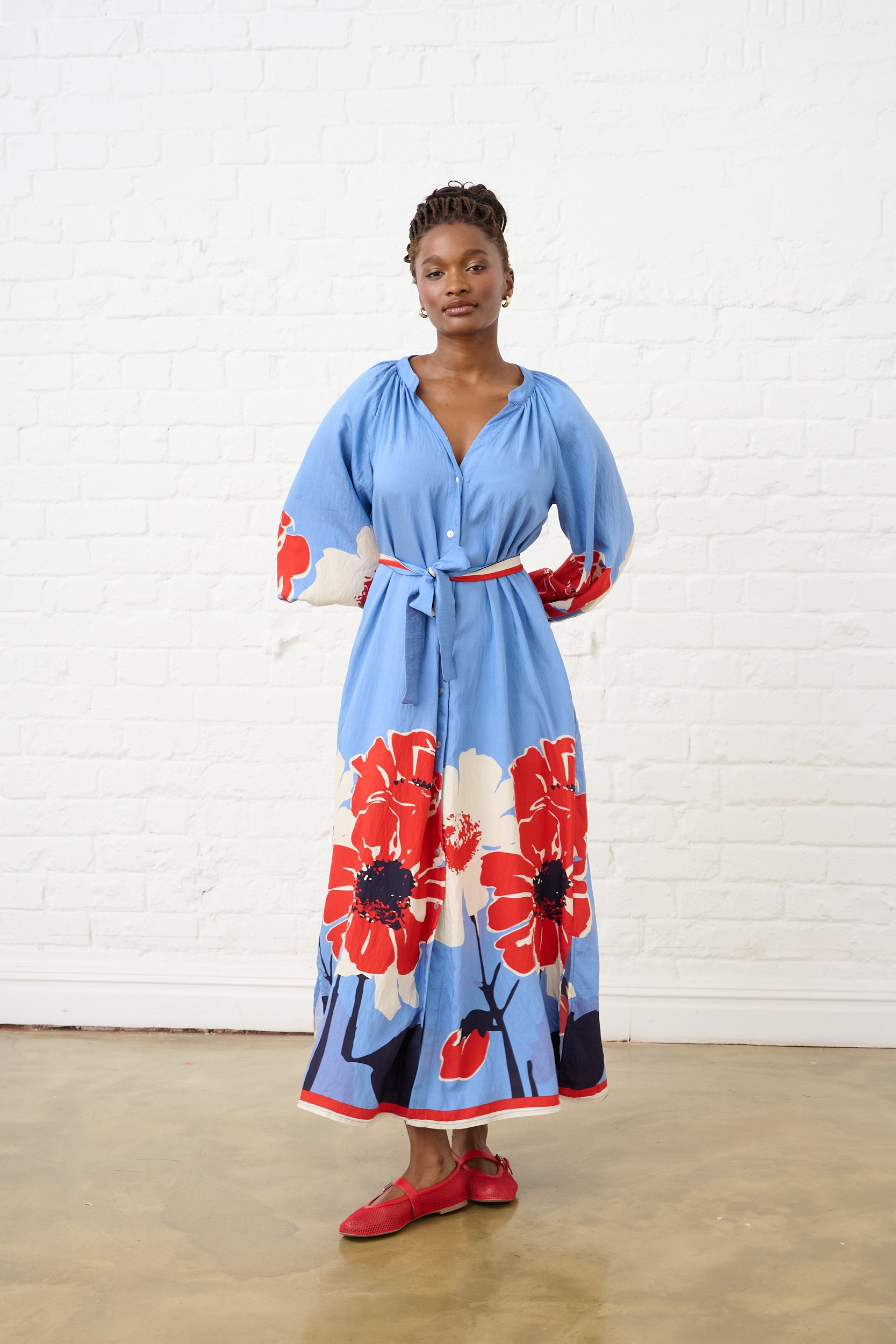 Model is wearing a long sleeve dress with a red and blue floral print