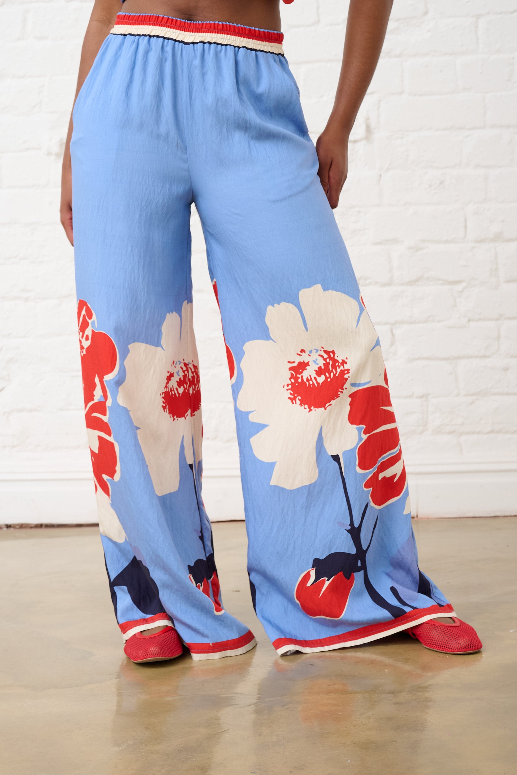 Model is wearing blue and red full length pants with floral print 