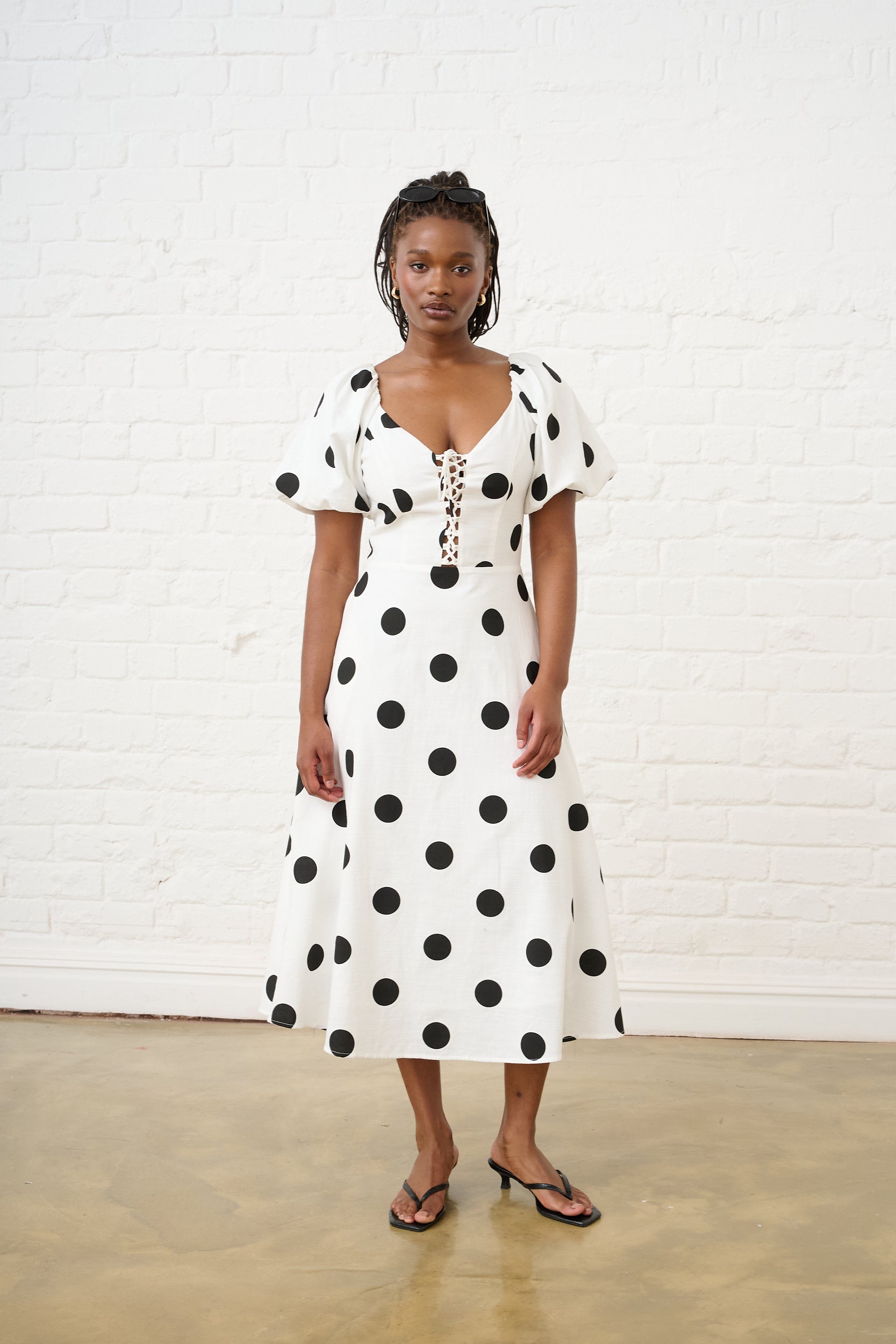 Model is wearing a long dress with black and white spot print 