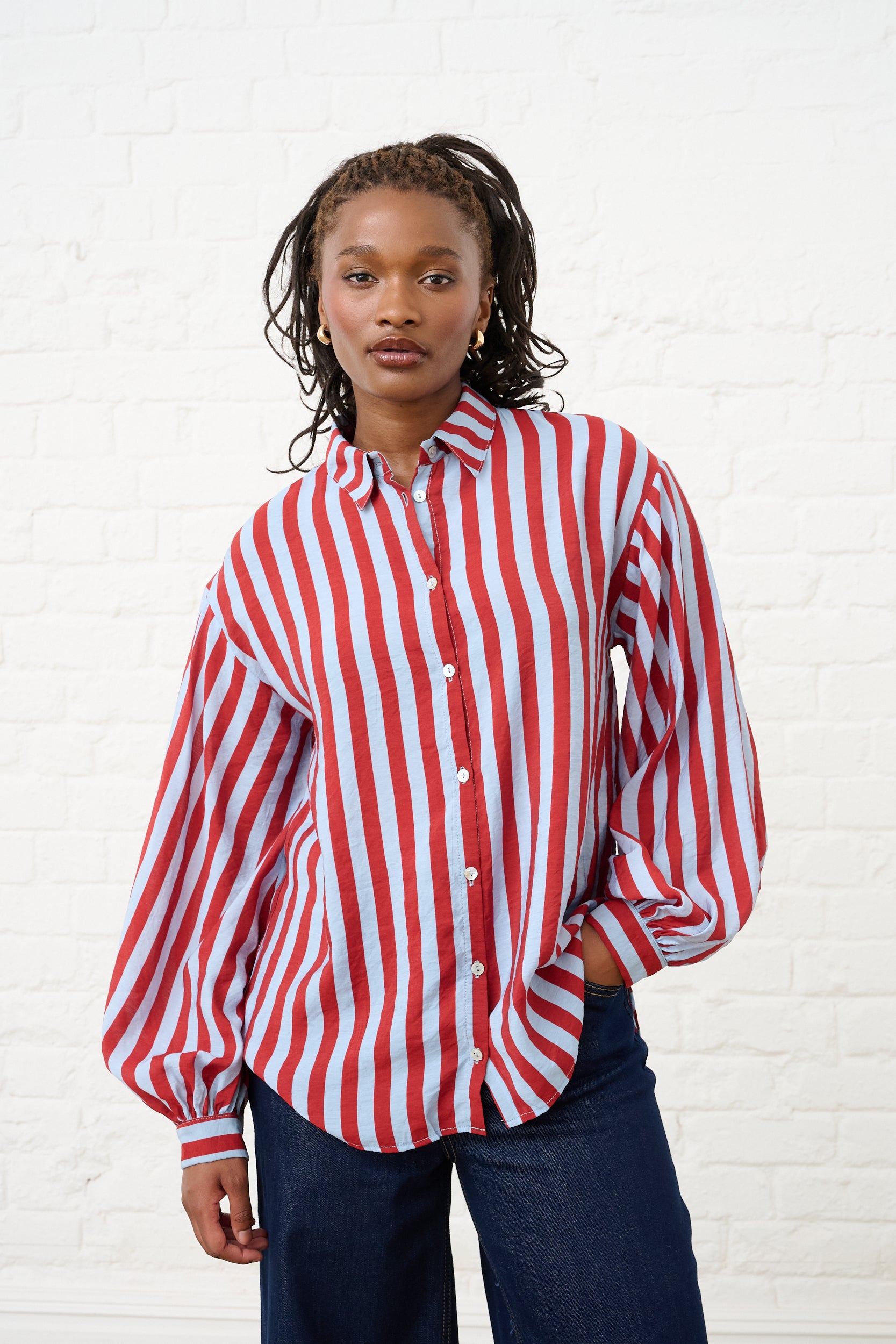 Model is wearing a blue and red striped shirt with blue jeans