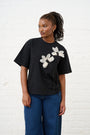 Model is wearing a black T shirt with white floral applique