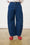 Model is wearing dark wash denim barrel jeans with red shoes and a white shirt 