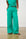 Model is wearing green linen pants with black sandals 