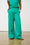 Model is wearing green linen pants with black sandals 