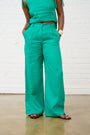 Model is wearing green linen pants with black sandals 