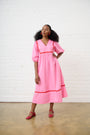 Model is wearing a pink dress with red shoes
