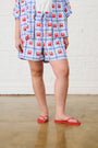 Model is wearing crab printed shorts in blue and red with red slops 