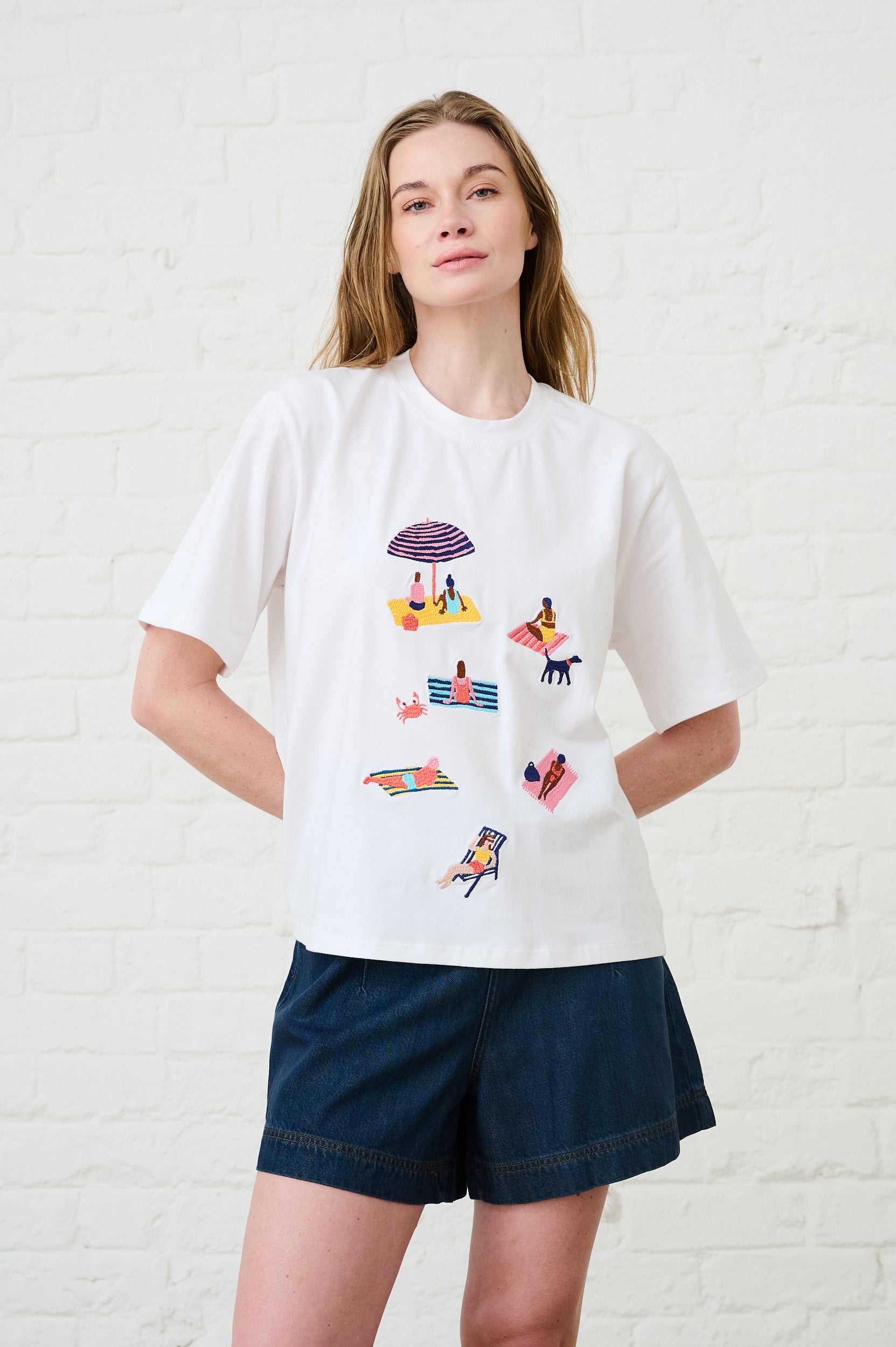 Model is wearing a white T-Shirt with beach scene on it and black shorts 