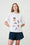 Model is wearing a white T-Shirt with beach scene on it and black shorts 
