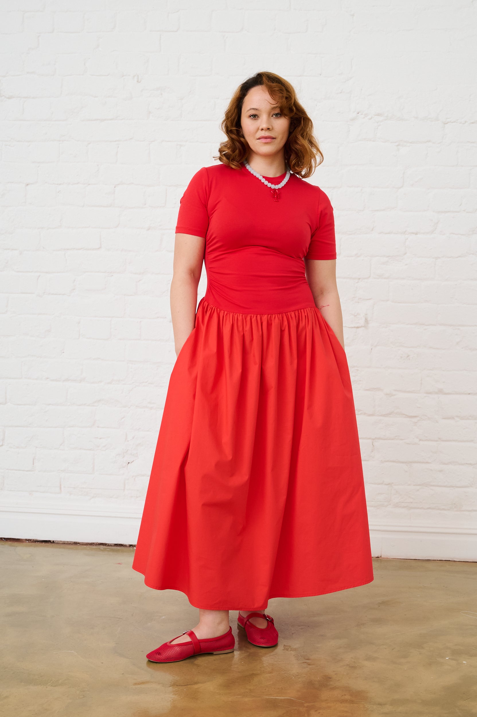 Model is wearing a coral short sleeve dress with red shoes