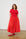 Model is wearing a coral short sleeve dress with red shoes