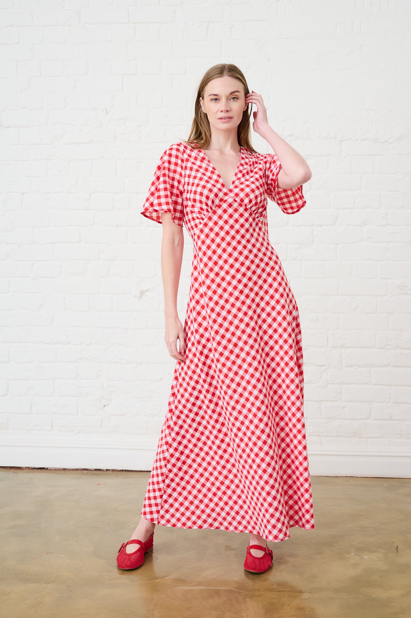 Model is wearing a red short sleeve gingham dress with red shoes 