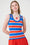 Model is wearing an orange, blue and white striped knit vest with orange shorts and a lobster necklace by Me&B