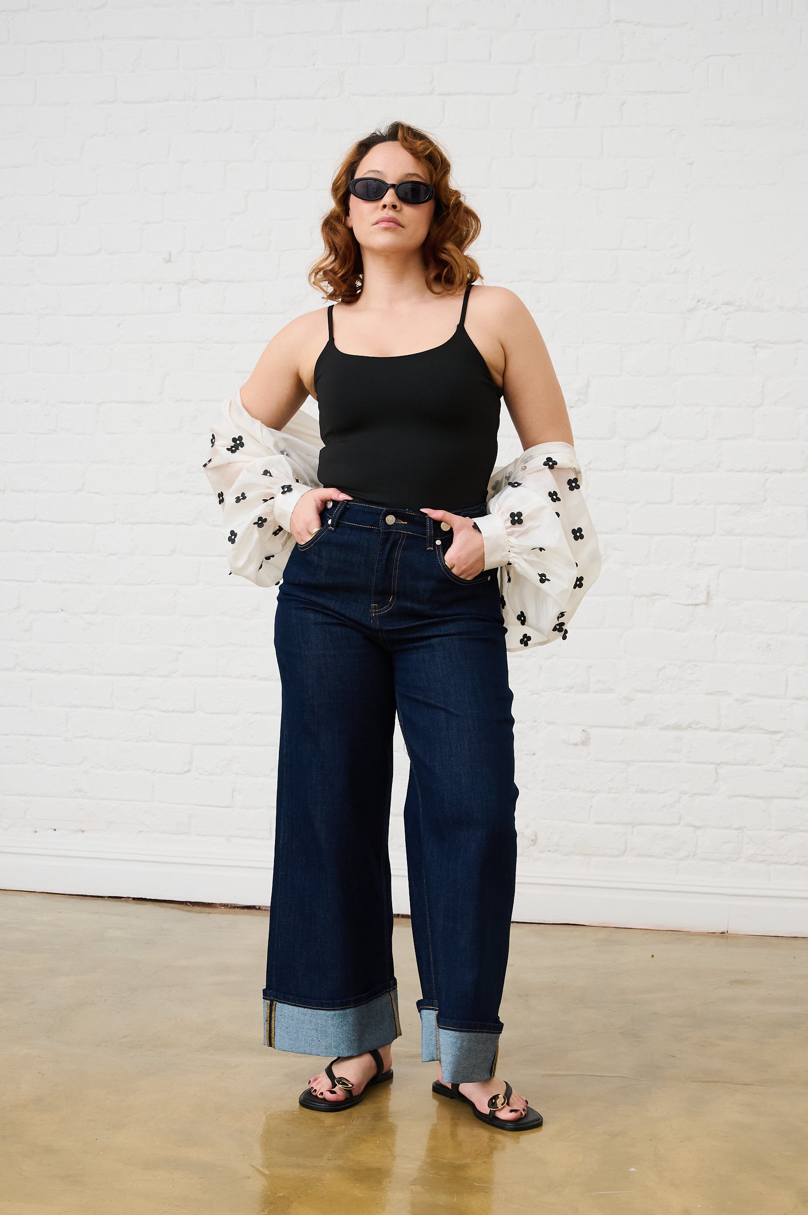 Model is wearing a black cami, turn up jeans and sandals
