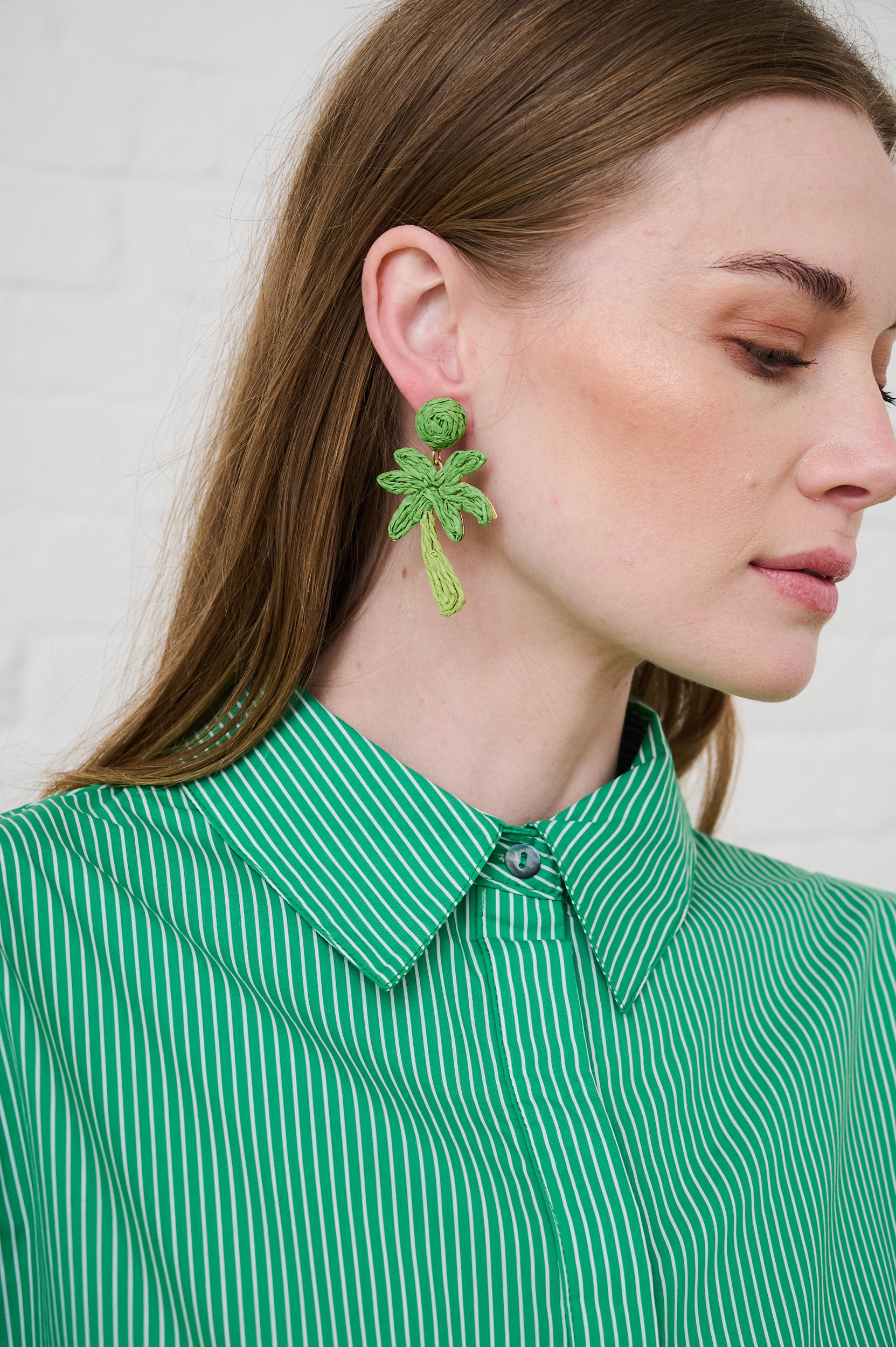 Model is wearing green palm tree earrings and a green shirt