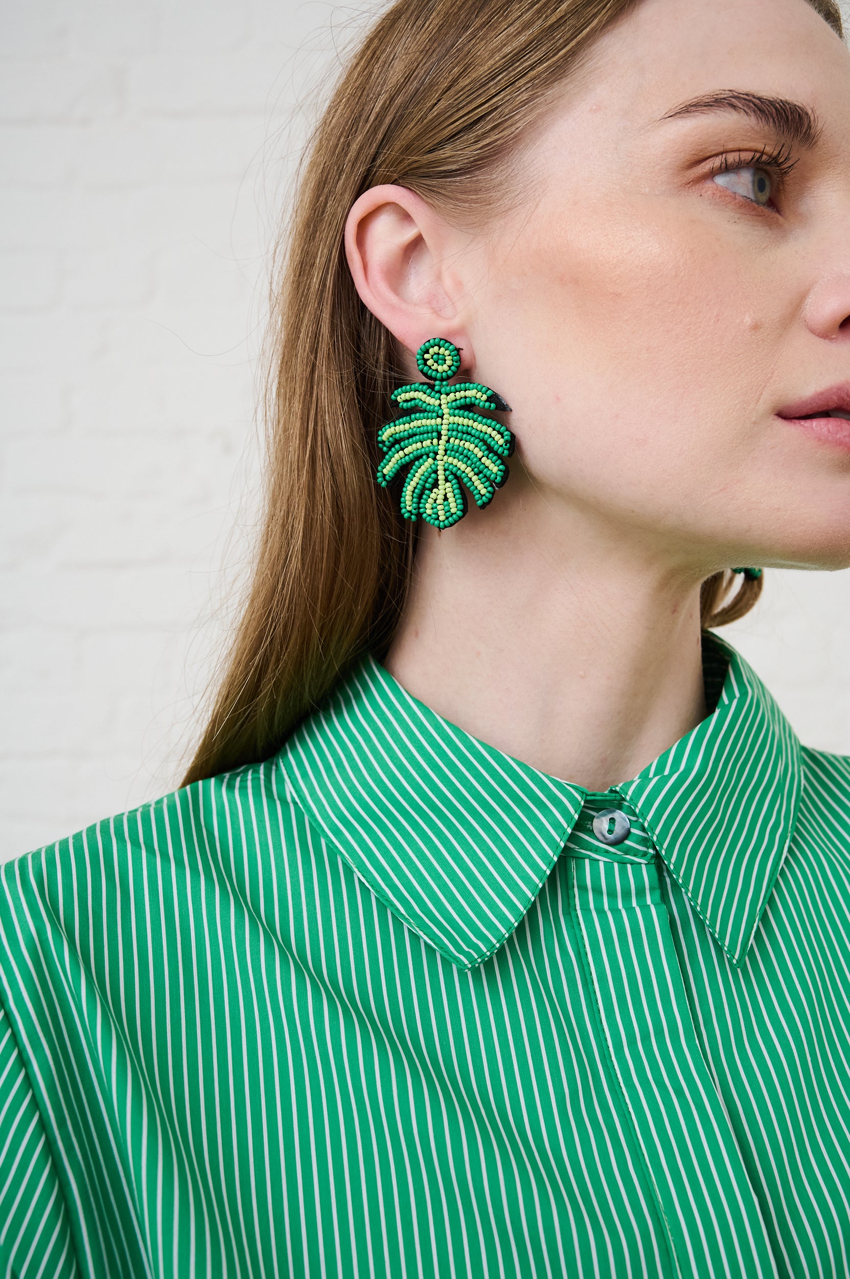 Model is wearing green and yellow beaded earrings and a green shirt