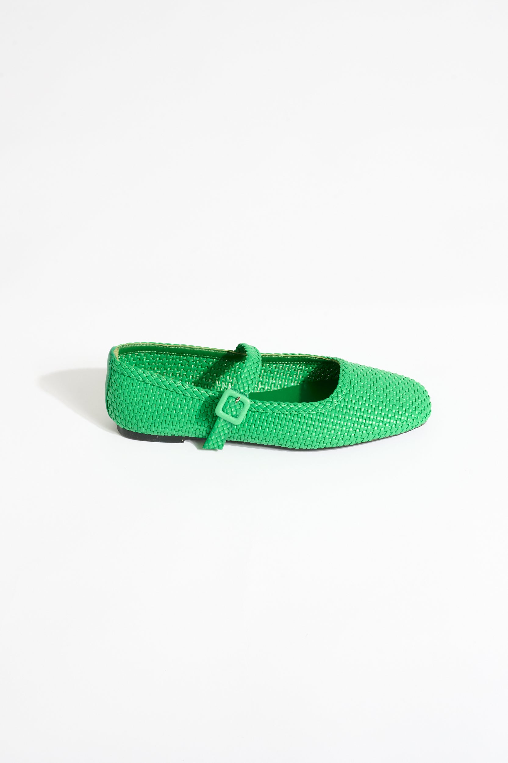 Green flat shoe with a strap on a white background