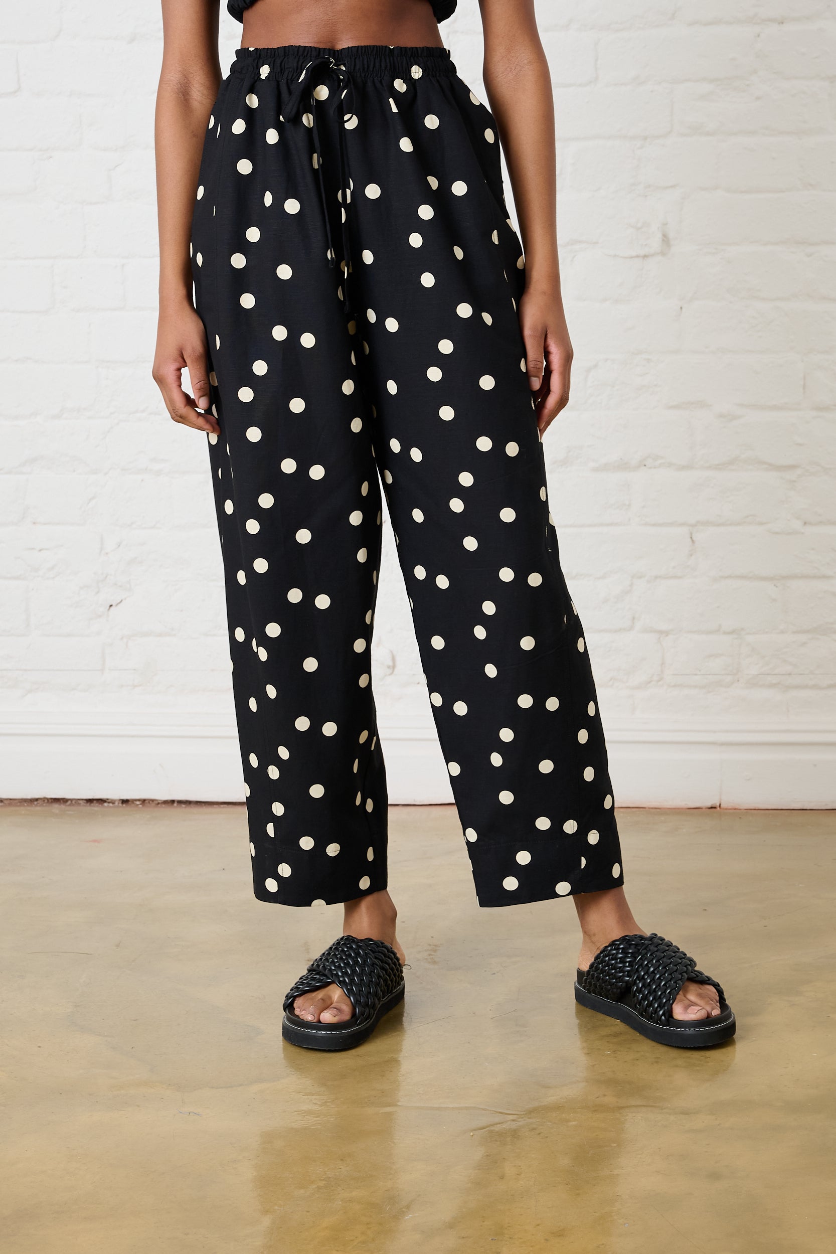 Model is wearing black and white spot pants with black sandals