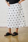 Model is wearing a black and white spotted skirt with black sandals 