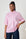 Woman wearing a pink and green striped shirt against a white brick wall.