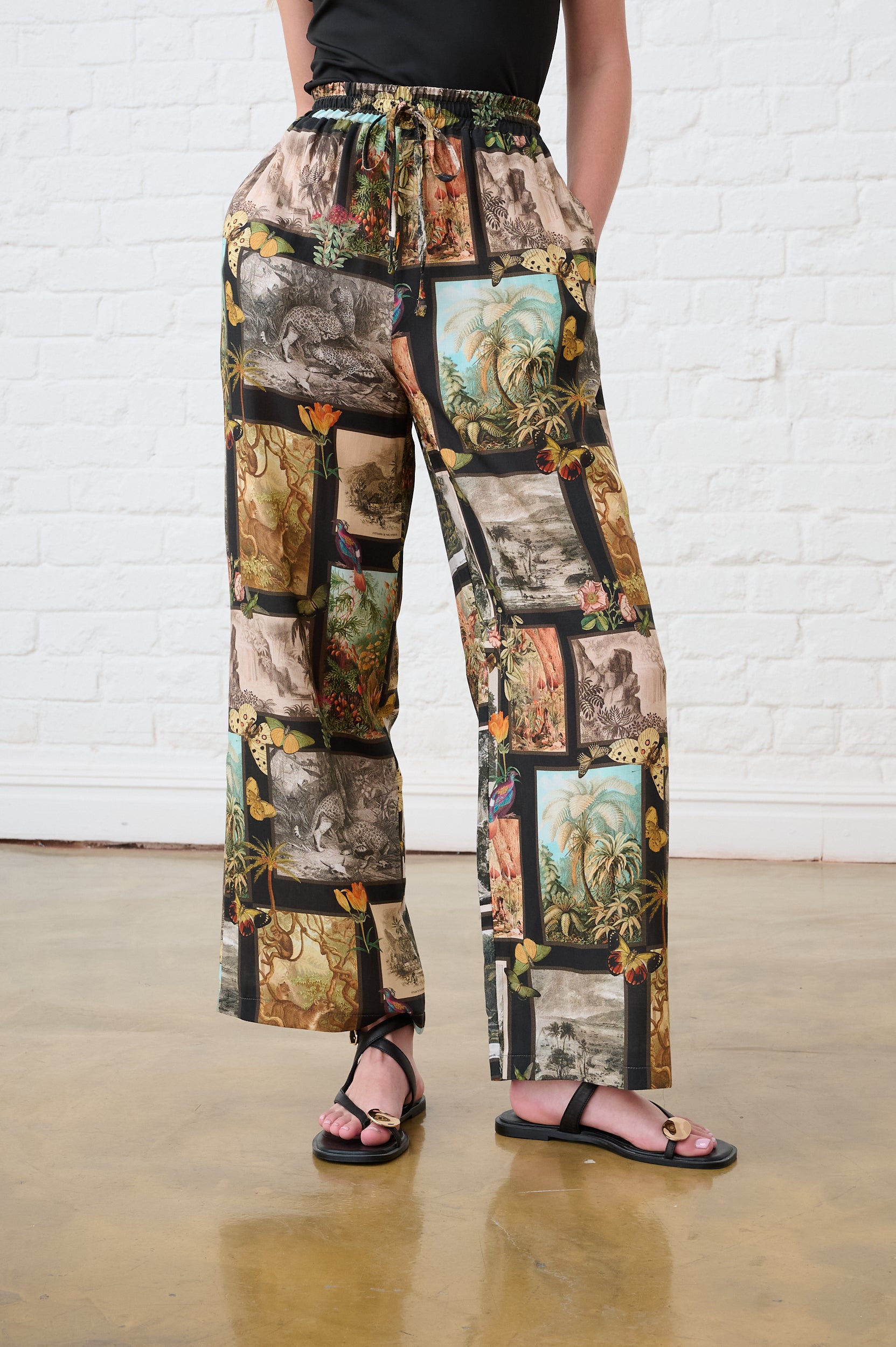 Model is wearing a gallery printed pants with a black Cami and Black Sandals