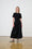 Model is wearing a black short sleeve combo dress with white and black ballet flats 