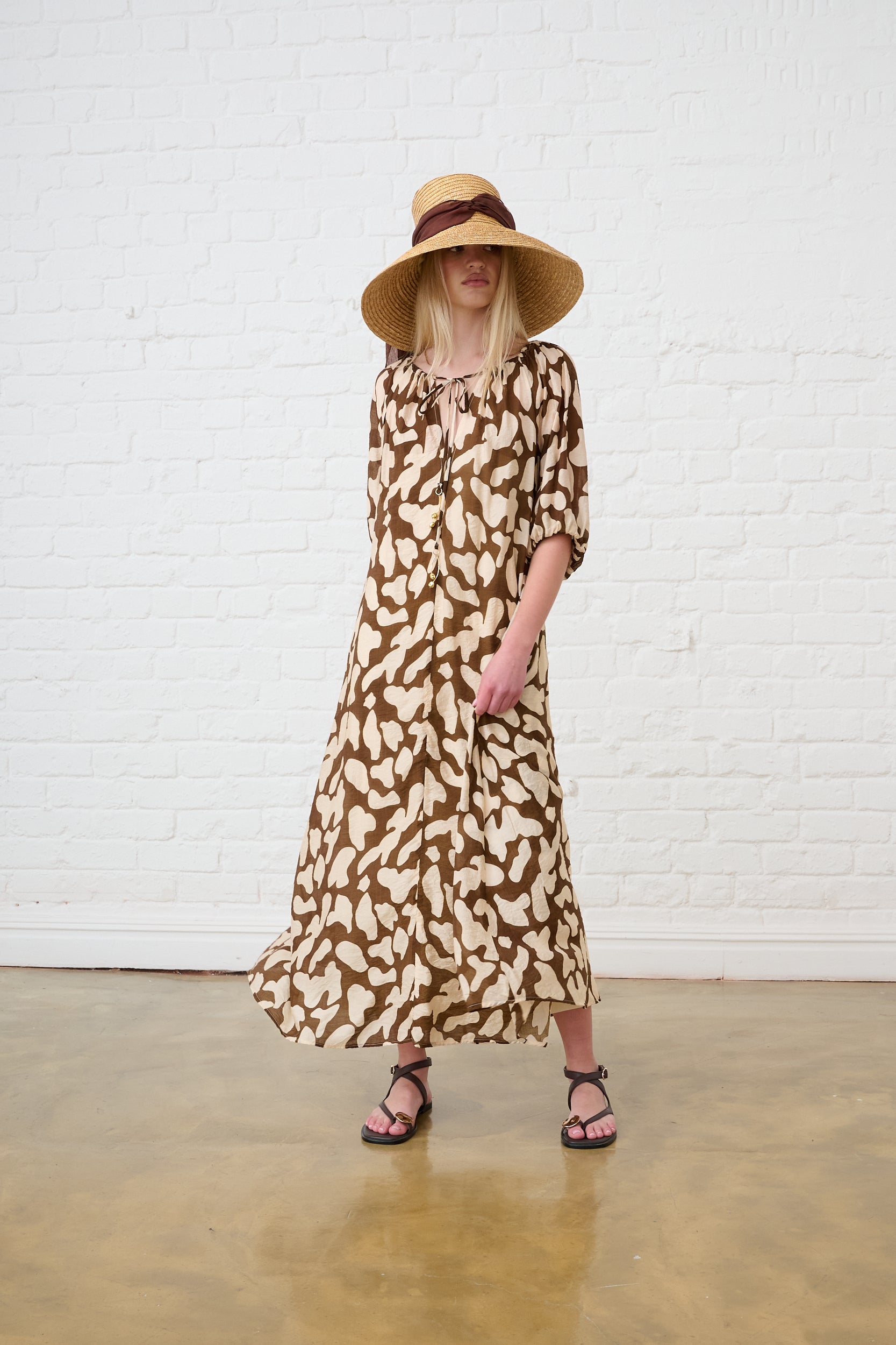 Model is wearing a brown and milk printed tunic dress, with brown sandals