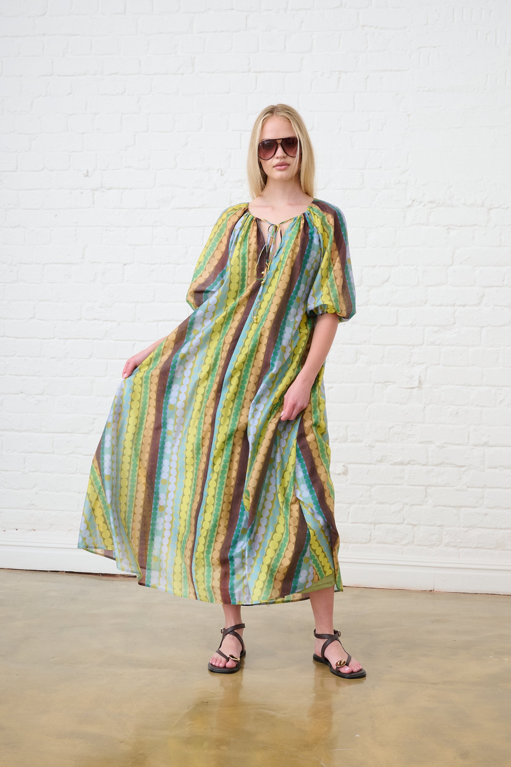Model is wearing a maxi tunic dress with brown sandals 