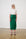 Model is wearing a green linen wrap skirt and a white blouse with brown sandals