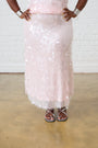 Model is wearing a light pink sequin skirt and silver sandals