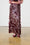 Model is wearing a burgundy sequin maxi skirt with burgundy flats
