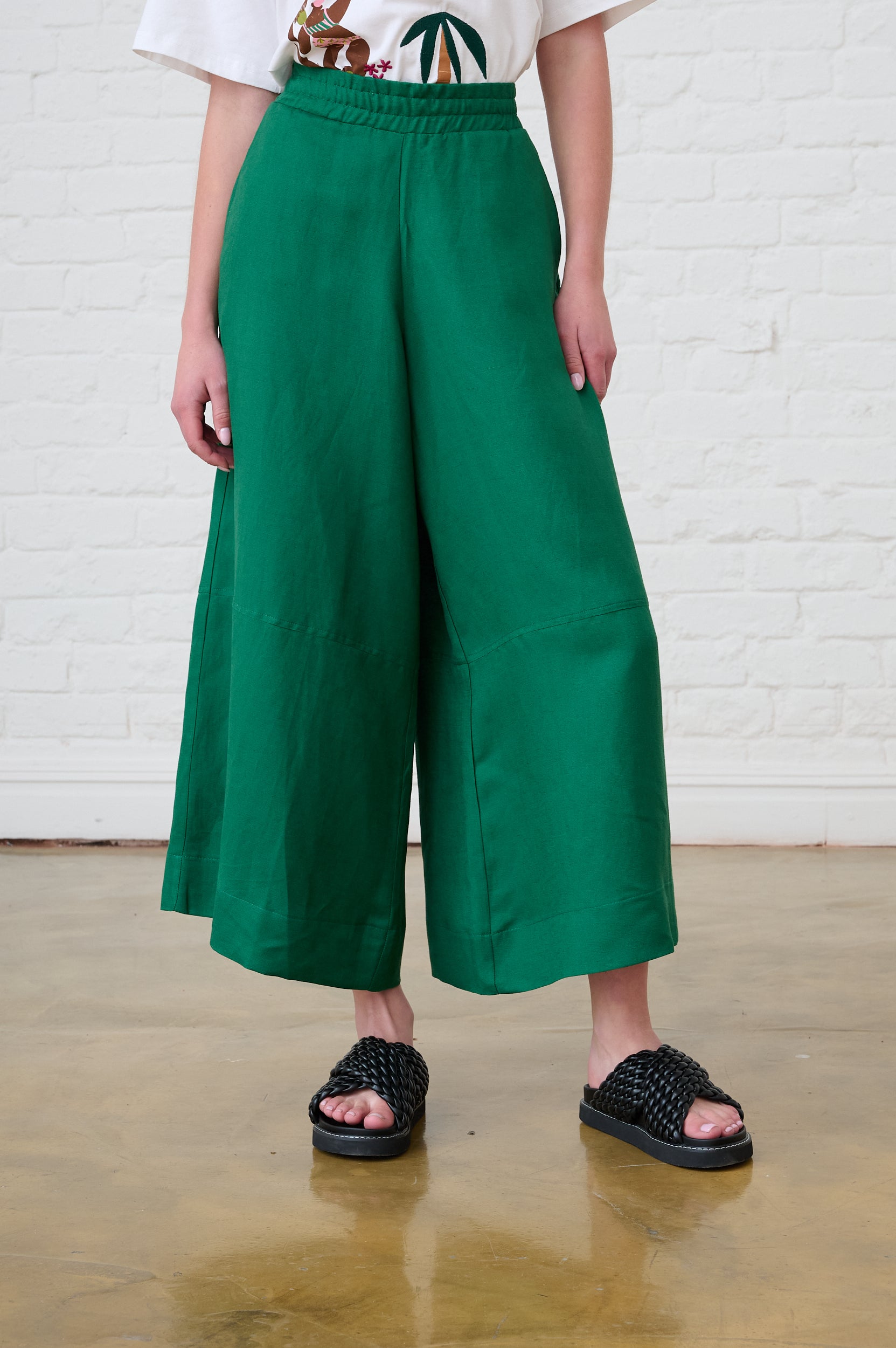 Model is wearing linen wide leg forrest green pants with black sandals