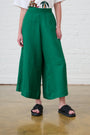Model is wearing linen wide leg forrest green pants with black sandals