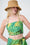 Model is wearing a green and yellow bandeue top with a straw hat 
