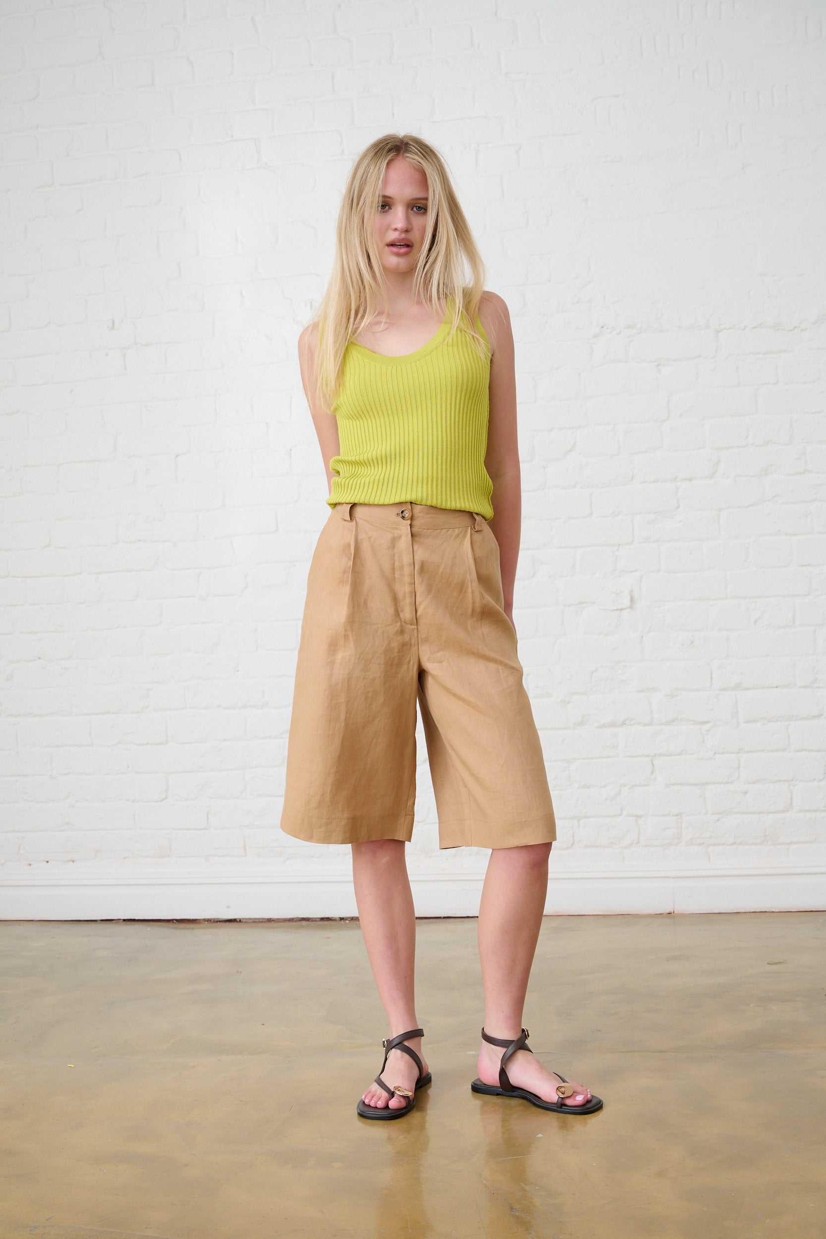 Model is wearing a lime vest with brown bermuda shorts and sandals