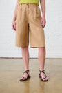 Model is wearing brown bermuda shorts above the knee with brown sandals