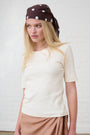 Model is wearing a short sleeve cream ribbed top with a chocolate brown spot head band 