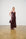 Woman wearing a sequin dress holding a handbag against a white wall.