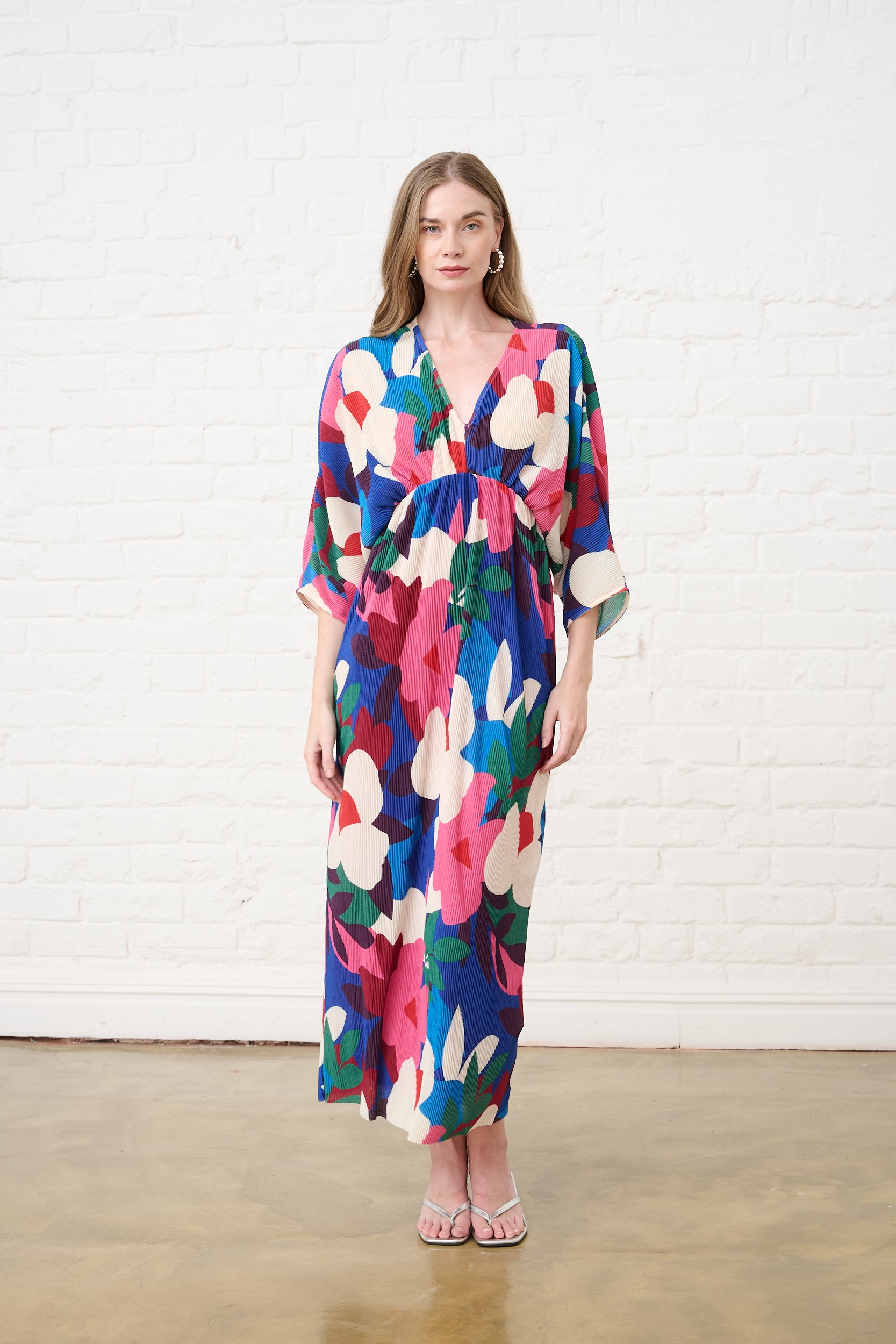 Model is wearing a colourful dress with silver heels.