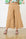 Model is wearing wide leg brown linen pants with brown sandals