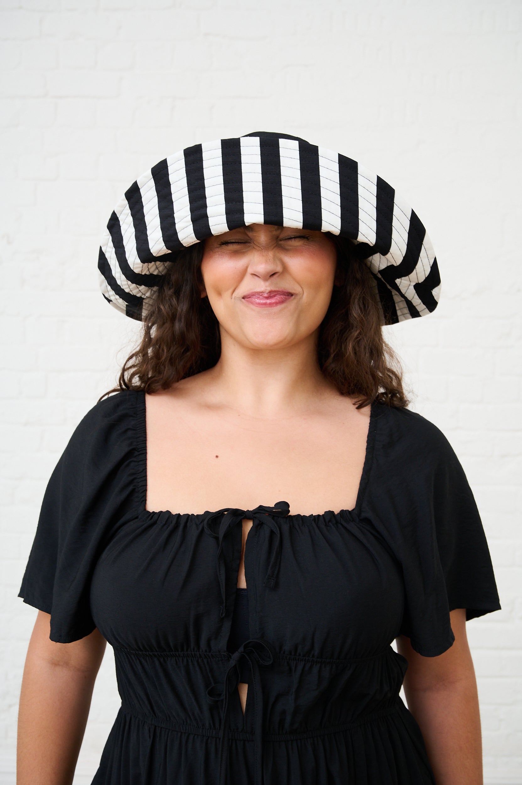Woman wearing a black and white striped hat against a white background