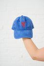 Blue cap with red lobster design held by a person against a white background