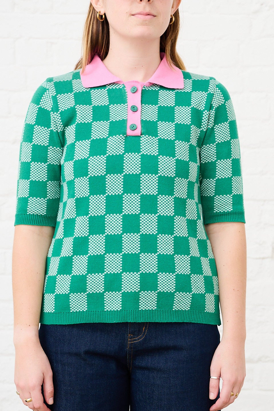 Model is wearing a green knit top with a pink collar